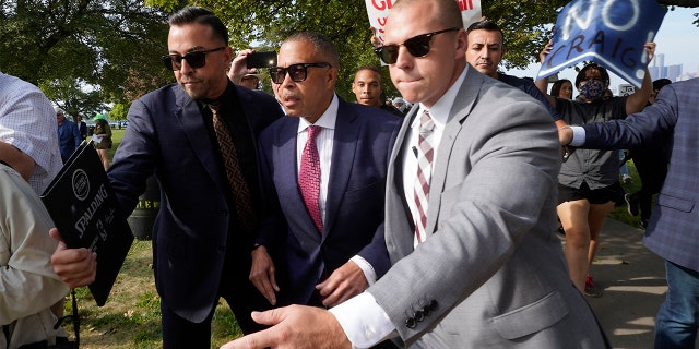 FILE - James Craig, center, a former Detroit Police chief, is escorted past protesters at a news conference on Belle Isle in Detroit, Tuesday, Sept. 14, 2021, where he announced he is a Republican candidate for governor of Michigan.