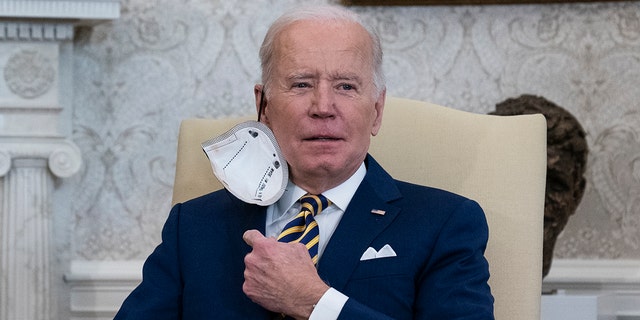 President Biden removes his protective face mask before speaking during a meeting with the Qatar's Emir Sheikh Tamim bin Hamad Al Thani in the Oval Office of the White House, Monday, Jan. 31, 2022, in Washington.