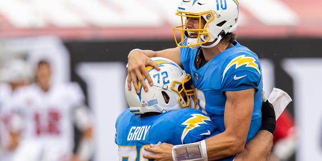 Justin Herbert # 10 of the Los Angeles Chargers celebrates with teammate Ryan Groy # 72 after throwing a touchdown during the third quarter of a game against the Tampa Bay Buccaneers at Raymond James Stadium on October 04, 2020 in Tampa, Florida.
