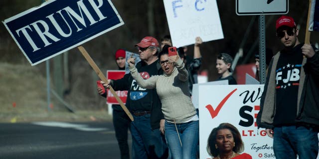 Protesters greet a motorcade with US President Joe Biden while it travels to Germanna Community College February 10, 2022, in Culpeper, Virginia. - Biden travels to Virginia to talk about lowering prescription drug costs. (Photo by Brendan Smialowski / AFP)