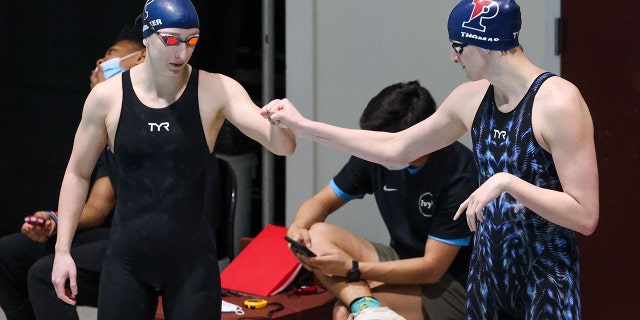 Lia Thomas fist-bumps teammate Catherine Buroker before the finals of the 500-yard freestyle during the Women’s Ivy League Swimming and Diving Championships at Harvard University.