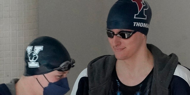 Penn's Lia Thomas, 对, smiles as Yale's Iszac Henig passes by as they prepare to swim in separate qualifying heats of the 100-yard freestyle at the Ivy League Women's Swimming and Diving Championships at Harvard University, 星期六, 二月. 19, 2022, in Cambridge, 弥撒.