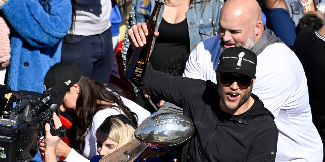 Los Angeles Rams quarterback Matthew Stafford holds up a bottle as offensive lineman Andrew Whitworth, right, holds the Vince Lombardi Super Bowl trophy during the team's victory parade in Los Angeles, Wednesday, Feb. 16, 2022, following their win Sunday over the Cincinnati Bengals in the NFL Super Bowl 56 football game.