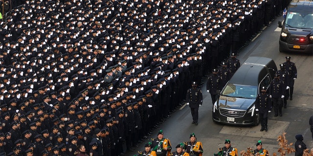 New York Police salute as a hearse carrying the casket of NYPD Officer Wilbert Mora is escorted down Fifth Avenue as it departs from St. Patrick's Cathedral after a funeral service for Mora, Wednesday, Feb. 2, 2022, in New York.