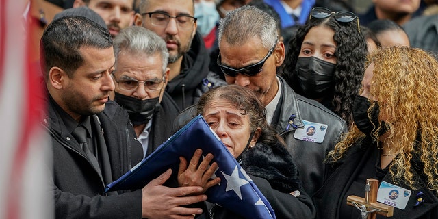 Family members of NYPD Officer Wilbert Mora react after receiving a flag from the honor guard following Mora's funeral at St. Patrick's Cathedral, Wednesday, Feb. 2, 2022, in New York. (AP Photo/John Minchillo)