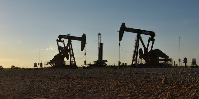 Pump jacks operate in front of a drilling rig in an oil field in Midland, Texas, Aug. 22, 2018. 