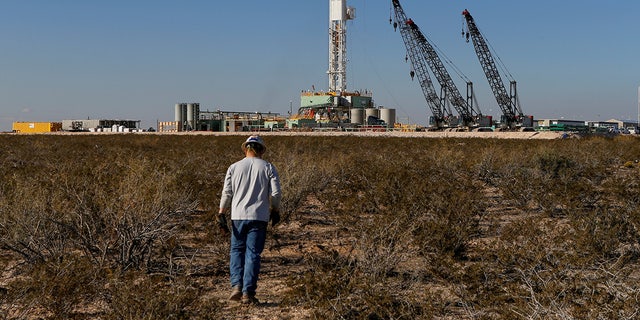 An oil worker walks toward a drill rig in Loving County, Texas, on Nov. 22, 2019.