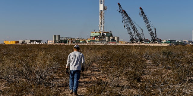 An oil worker walks toward a drill rig after placing ground monitoring equipment in the vicinity of the underground horizontal drill in Loving County, Texas, Nov. 22, 2019.