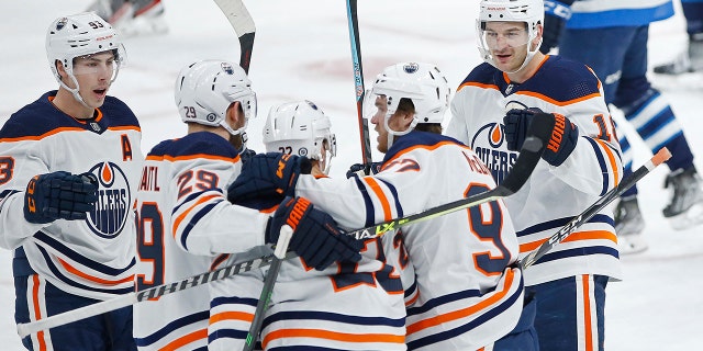 Edmonton Oilers' Zach Hyman (18) celebrates his goal against the Winnipeg Jets with teammates Ryan Nugent-Hopkins (93), Leon Draisaitl (29), Tyson Barrie (22), and Connor McDavid (97) during the first period of an NHL hockey game in Winnipeg, Manitoba, Saturday, Feb. 19, 2022.
