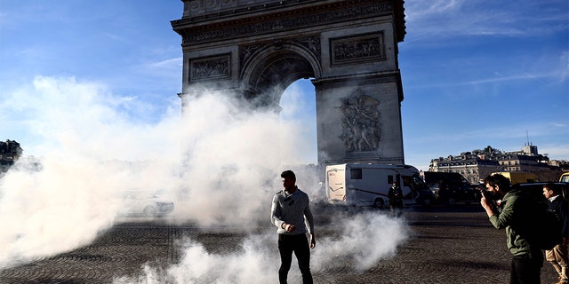A man walks through tear gas on the Place Charles De Gaulle in Paris Feb. 12, 2022, as convoys of protesters, "Convoi de la Liberte," arrived in the French capital. 