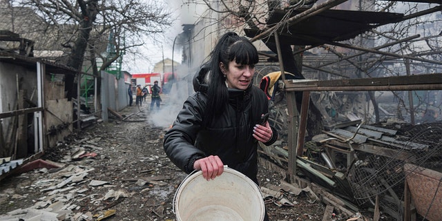 A woman walks past the debris in the aftermath of Russian shelling, in Mariupol, Ukraine, Thursday, Feb. 24, 2022. 