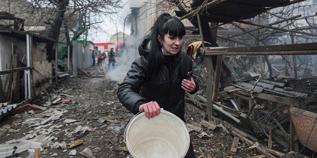 Женщина идет по завалам после российской бомбардировки Мариуполя, Украина, четверг, 24 февраля 2022 года.