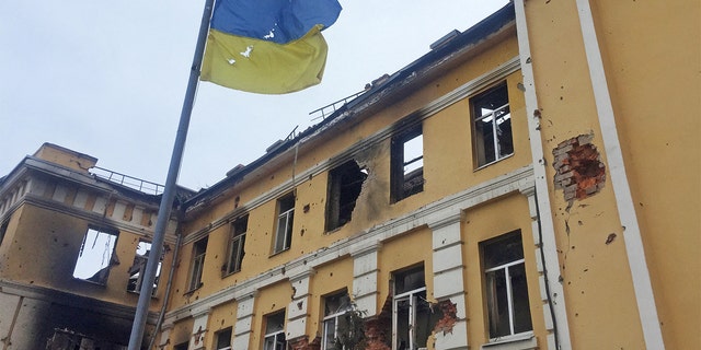 The Ukrainian national flag is seen in front of a school which, according to local residents, was on fire after shelling, as Russia's invasion of Ukraine continues, in Kharkiv, Ukraine, Feb. 28, 2022, four days after the Russia-Ukraine war began.