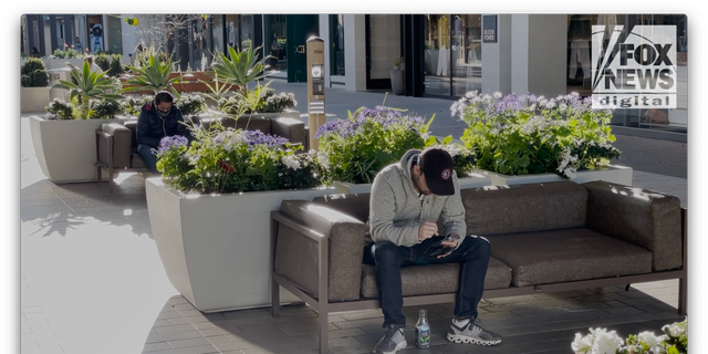 Two men on their phones at Stanford Shopping Center in Palo Alto, Calif. 