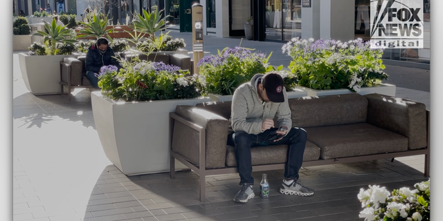 Two men on their phones at Stanford Shopping Center in Palo Alto, Calif.