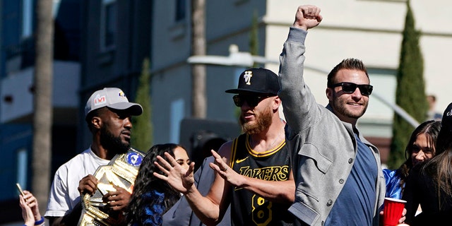 Los Angeles Rams wide receiver Cooper Kupp, second from right, reaches out for a football being tossed by a fan as head coach Sean McVay, right, reacts as they ride on a bus during the team's victory parade in Los Angeles, Wednesday, Feb. 16, 2022, following their win Sunday over the Cincinnati Bengals in the NFL Super Bowl 56 football game.