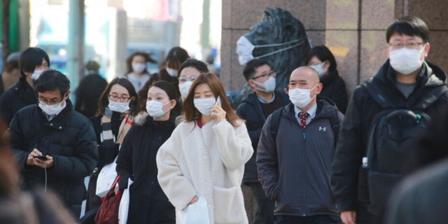 People wearing face masks to protect against the spread of the coronavirus walk on the street in Tokyo on Feb. 24, 2022. (AP Photo/Koji Sasahara)
