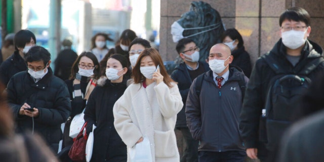 People wearing face masks to protect against the spread of the coronavirus walk on the street in Tokyo on Feb. 24, 2022. (AP Photo/Koji Sasahara)