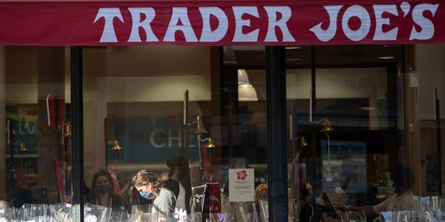 FILE: An employee is seen through a window working a register in a patch of sunlight at Trader Joe's in New York City's Chelsea neighborhood. (Photo by Alexi Rosenfeld/Getty Images)