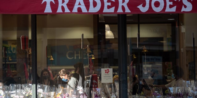 FILE: An employee is seen through a window working a register in a patch of sunlight at Trader Joe's in New York City's Chelsea neighborhood. (Photo by Alexi Rosenfeld/Getty Images)