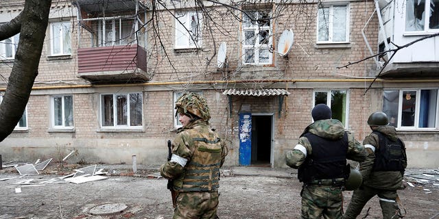 Militants of the self-proclaimed Donetsk People's Republic stand in front of an apartment building, which locals said was damaged by recent shelling, in the separatist-controlled town of Yasynuvata (Yasinovataya) in the Donetsk region, Ukraine February 24, 2022.
