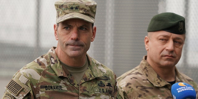 US Army General Christopher Donahue, left, commanding general of the 82nd Airborne Division, and Polish General Wojciech Marchwica speak to journalists after unloading vehicles from a transport plane arriving from Fort Bragg at the Rzeszow-Jasionka airport in southeastern Poland, on Sunday, Feb. 6, 2022.