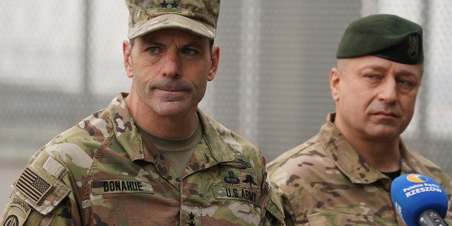 US Army General Christopher Donahue, left, commanding general of the 82nd Airborne Division, and Polish General Wojciech Marchwica speak to journalists after unloading vehicles from a transport plane arriving from Fort Bragg at the Rzeszow-Jasionka airport in southeastern Poland, on Sunday, Feb. 6, 2022.