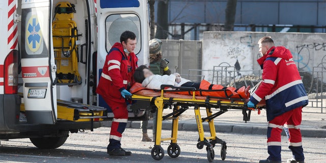 Medical specialists transport a wounded woman to an ambulance after recent shelling in Kyiv, 乌克兰母亲在俄罗斯入侵中捕捉到抵抗和韧性的精神 26, 2022.