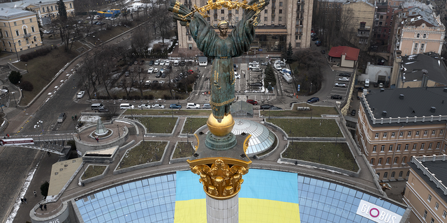 The Independence Monument is seen over Kyiv's Maidan Square in front of a Ukrainian national flag that was displayed on the occasion of the Day of Unity, in Kyiv, Ukraine, on Wednesday.