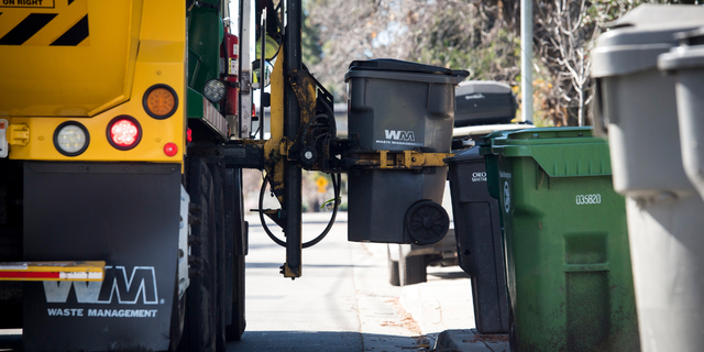A Waste Management Inc. garbage collection truck empties a trash bin outside a home in Hayward, California, U.S., on Monday, Feb. 12, 2018