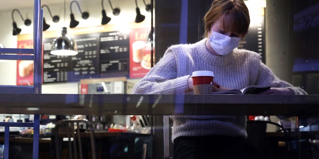 Tourist Elizabeth Senter wears a mask as she reads her book at a coffee shop Dec. 21, 2021, in Washington, DC.