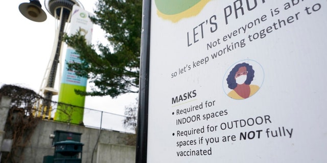A sign near the Space Needle notes that masks are required for indoor spaces, Thursday, Feb.  17, 2022, in Seattle. 