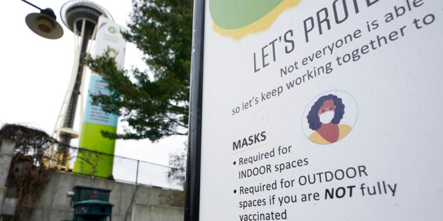 A sign near the Space Needle notes that masks are required for indoor spaces, Thursday, Feb. 17, 2022, in Seattle. Gov. Jay Inslee said Thursday that the statewide indoor mask mandate in Washington state will lift on March 21, 2022, including at schools and child care facilities.