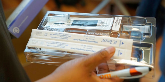 Kristin Travis, a community outreach doula, holds a home COVID-19 test kit Thursday, Feb. 3, 2022, while picking up supplies at Open Arms Perinatal Services before going out to visit some of her clients in Seattle.