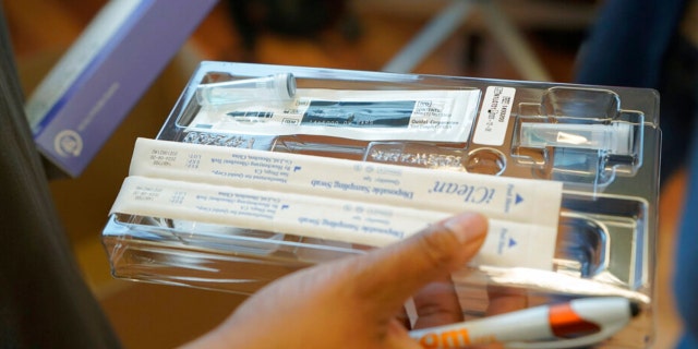 Kristin Travis, a community outreach doula, holds a home COVID-19 test kit Thursday, Feb. 3, 2022, while picking up supplies at Open Arms Perinatal Services before going out to visit some of her clients in Seattle.