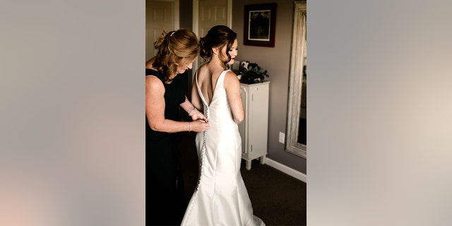 Mother and daughter attend to the bride's beautiful wedding dress. Before this happy time, there was drama, upset — and a medical emergency.