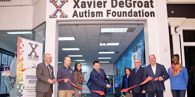 Xavier DeGroat, center, at the ribbon cutting ceremony for his Autism History Museum  at the Meridian Mall in Okemos, Mich, on Feb. 4, 2022.