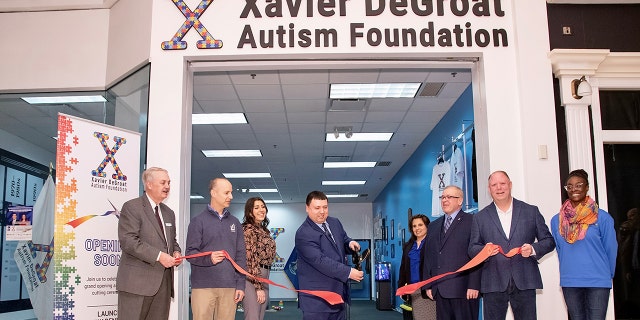 Xavier DeGroat, center, at the ribbon cutting ceremony for his Autism History Museum at the Meridian Mall in Okemos, Mich, on Feb. 4, 2022.