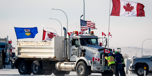 Drivers work to move a gravel truck after a breakthrough resolved the impasse where anti-COVID-19 vaccine mandate demonstrators blocked the highway at the busy U.S. border crossing in Coutts, Alberta, Wednesday, Feb. 2, 2022.