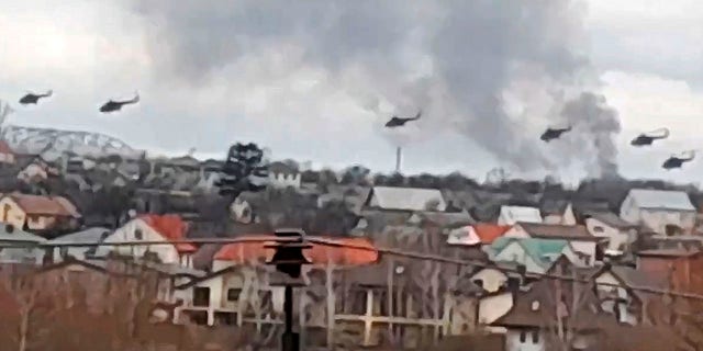 Военные вертолеты, предположительно российские, пролетают над окраиной Киева, Украина, в четверг, 24 февраля 2022 года.