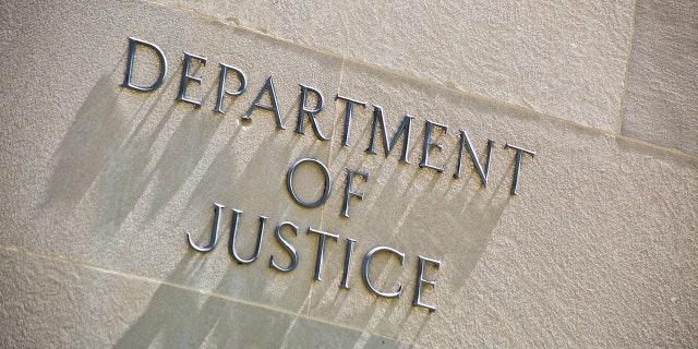 The entrance signage for the United States Department of Justice Building in Washington D.C., USA. The Department of Justice has charged a man accused of purchasing dozens of firearms in a six-month span in which some were used in crimes. 