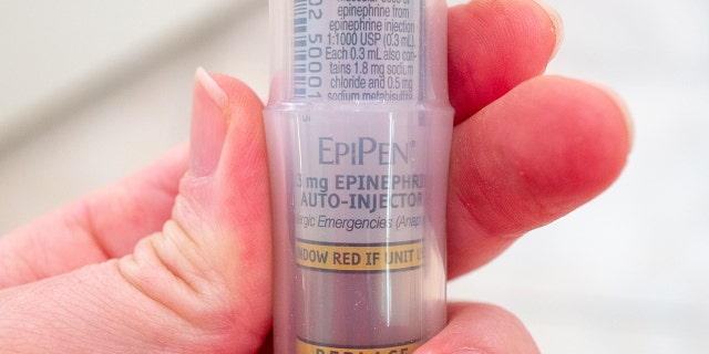 Close-up of an EpiPen logo on an epinephrine auto-injector held in a person's hand, Feb. 17, 2021.