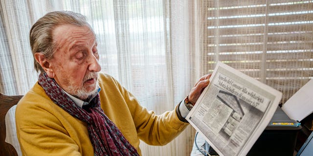 Luigi Boni, a 95-year-old Florentine retiree, shows a newspaper article about the "Adopt-a-bill" initiative, a plea to wealthier residents to help pay for the utility bills of those elderly people in need, during an interview with The Associated Press in his house in Florence, Italy, Thursday, Feb. 17, 2022. 