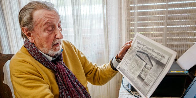 Luigi Boni, a 95-year-old Florentine retiree, shows a newspaper article about the "Adopt-a-bill" initiative, a plea to wealthier residents to help pay for the utility bills of those elderly people in need, during an interview with The in his house in Florence, Italy, Thursday, Feb. 17, 2022.