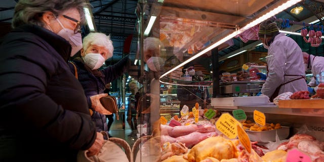 Two elderly women buy food in a market in Florence, Italy, Thursday, Feb. 17, 2022. 