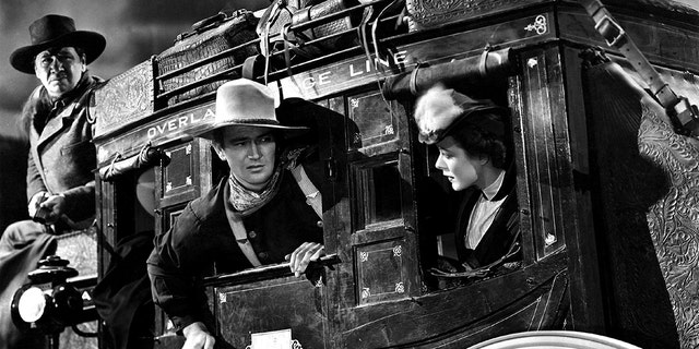 1939:  L-R George Bancroft, John Wayne and Louise Platt on the set of the movie 'Stagecoach' in 1939. 