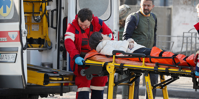 Medical specialists transport a woman, who was wounded in the shelling of an apartment building, to an ambulance as her husband stands nearby in Kyiv, Ukraine, Feb. 26, 2022.