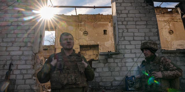 Ukrainian servicemen stand by a destroyed house near the frontline village of Krymske, Luhansk region, in eastern Ukraine, Saturday, Feb. 19, 2022.