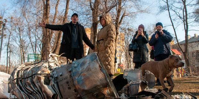 Люди стоят рядом с осколками военной техники на улице после очевидного российского рейда в Харькове, Украина, четверг, 24 февраля 2022 года.