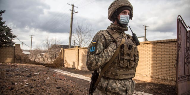 A Ukrainian soldier passes by houses in the village of Novoluhanske, Luhansk region, Ukraine, Saturday, Feb. 19, 2022.